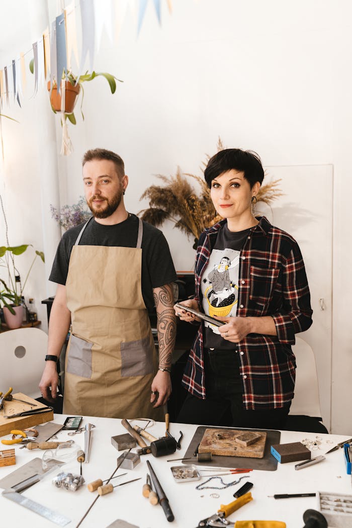 Two adults crafting in a bright workshop with woodworking tools and materials.