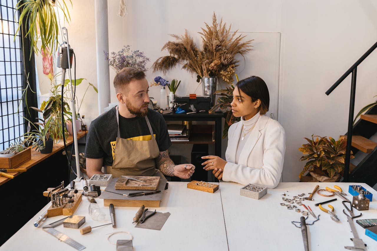 Man and woman discussing jewelry design in an artisan studio.