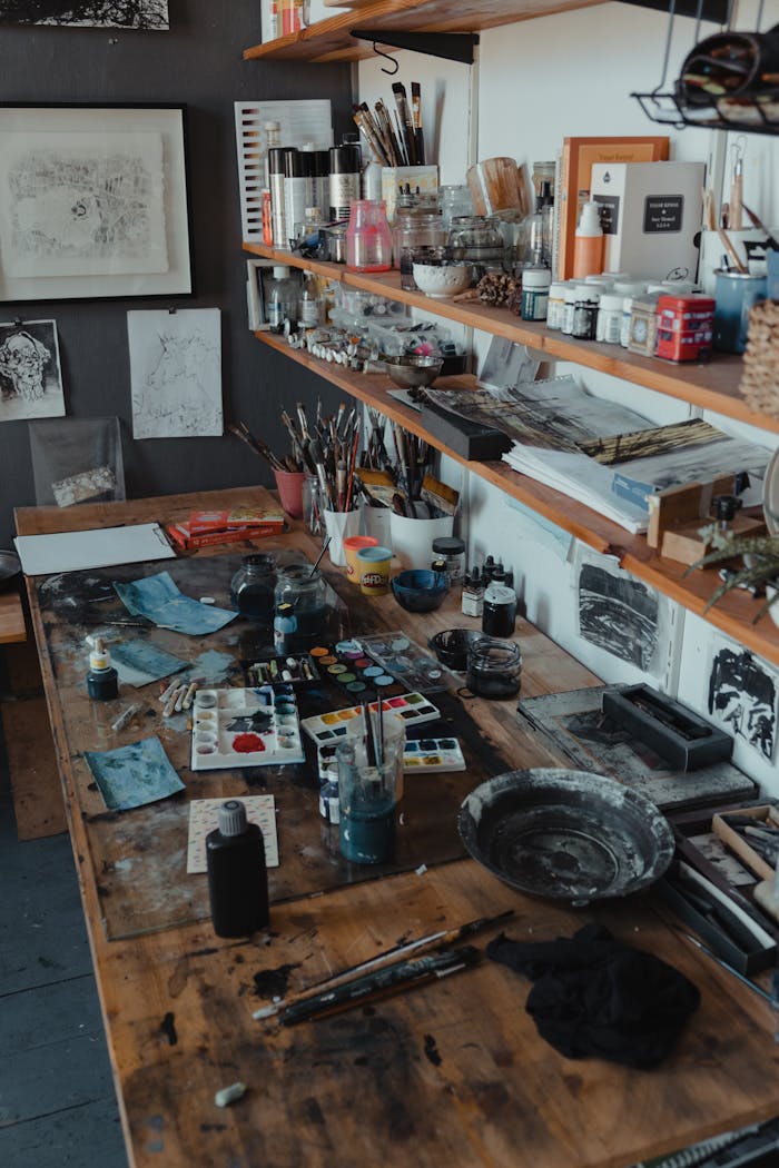 Artistic workshop space filled with paints, brushes, and art tools on a wooden desk.
